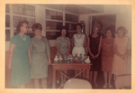 Group of Women Stand Around Table With Dolls