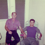 Two men sitting and holding hands