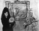 Louisa and Rose Esperante Dressed in Spanish Attire Stand in Front of a Picture of Don Quixote at La Verbena Del Tabaco Festival by Burgert Brothers