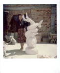 Adela Gonzmart standing next to a replica of the Patio room's sculpture, "Love and the Dolphin"