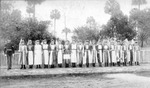 Young women stand in a line and hold flags of the world by Ensminger Brothers