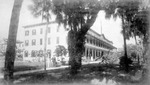 Man holding a shovel stands outside the Hotel Indian River by Ensminger Brothers