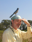 Peter Merritt shields his eyes from the sun while a Florida scrub-jay sits on his head looking away