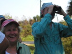 Soo Whiting smiles widely while Peter Merritt looks through binoculars during a Florida Ornithological Society (FOS) birding trip in Leesburg