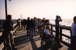 A crowd of Florida Ornithological Society (FOS) members observe seabirds from both sides of a pier in Jacksonville, Florida