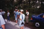 A dozen Florida Ornithological Society members stand beside a tree-lined road in Jacksonville, Florida