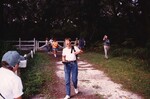 Eight Florida Ornithological Society members walk up a dirt driveway in Jacksonville, Florida