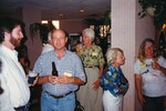 A cluster of six Florida Ornithological Society members stand chatting with drinks in hand during a meeting in Jacksonville, Florida