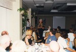 Reed Bowman and Peggy Powell stand speaking while other Florida Ornithological Society members sit scattererd among a large banquet room in Jacksonville, Florida