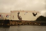 Two Citgo oil reservoirs stand painted with illustrations of different bird species at the Port of Tampa