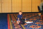 A young boy sits on the floor of a conference room beside snacks and toy cars at a Florida Ornithological Society meeting