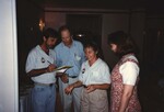 A bearded Florida Ornithological Society member writes on a legal pad with Bruce Hallett and two others during a FOS meeting