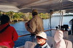 Guests view the shoreline on a boat tour behind a seated Ted Below in Fort Pierce, Florida