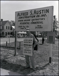 An Alfred S. Austin Construction Company employee strikes in front of the company's sign in Tampa, Florida