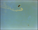 A professional parachuter trails yellow smoke through the sky while a second begins its descent at a air show in Tampa, Florida