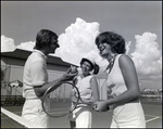 Three players chat animatedly by the net on the tennis courts at Bay Pointe Condominiums in Tampa, Florida, B