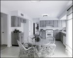 A small kitchen with wooden cabinets and a rattan breakfast table in Tampa, Florida, A