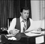 Jerry Bowmer reading Papers at his Desk, C by Skip Gandy