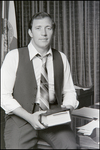 Jerry Bowmer Portrait Sitting on his Desk with Book in Hand, D by Skip Gandy