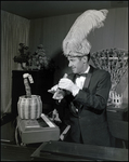 Musician Wearing a Hat With a Bird Plume Pretending to Hypnotize a Toy Snake by Skip Gandy