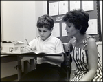 A Teacher Puts a Hand on Her Student's Shoulder While He Writes at Berkeley Preparatory School in Tampa, Florida by Skip Gandy