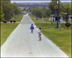 Two Children Ride Bicycles Down a Residential Street in Beverly Hills, Florida by Skip Gandy