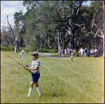 Boy Carries Fishing Rod During Picnic in Beverly Hills, Florida, A by Skip Gandy