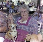 Woman Sits With Dog in Her Lap at German American Social Club Festival in Beverly Hills, Florida, A by Skip Gandy