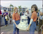 Two Women Hold Tiered Cake at Burnt Store Marina Seafood Festival in Punta Gorda, Florida, A by Skip Gandy