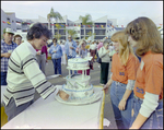 Three Women Inspect Tiered Cake at Burnt Store Marina Seafood Festival in Punta Gorda, Florida, A by Skip Gandy