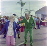 Man Walks With Partner at Burnt Store Marina Seafood Festival in Punta Gorda, Florida by Skip Gandy