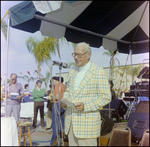 Man in Yellow Gingham Jacket Reads Into Microphone at Burnt Store Marina Seafood Festival in Punta Gorda, Florida, A by Skip Gandy