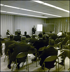 Sitting Crowd Watching Man Speak Next to Whiteboard, Tampa, Florida, A by George Skip Gandy IV