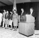 Speakers and Staff Behind a Podium at the Harbour Island Hotel, A by George Skip Gandy IV