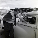 Man Engaging with a Vehicle at a Parking Lot, C by George Skip Gandy IV