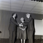 Men Shaking Hands Next to Woman on Stage for Master Charge by George Skip Gandy IV