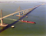 Tugboat Dixie Commander Pushing a Dredge Under the Sunshine Skyway Bridge, Tampa Bay, Florida, A by George Skip Gandy IV