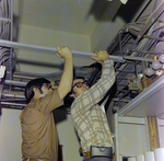 Two men Checking the Metal Framework Along with Electrical Wiring, A by George Skip Gandy IV