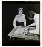 Woman Looking over a Person Working on a Signboard at Magic Systems, M by George Skip Gandy IV