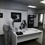 Man and Woman Talking at Desk at Walker & McLane in Tampa, D by George Skip Gandy IV