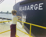 Woman Breaking Bottle Against Seabarge 251, Misener Industries, A by George Skip Gandy IV
