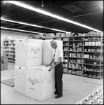 Man Standing Next to Stack of Large Boxes in Anderson Surgical Supply Company Storage Room by Skip Gandy