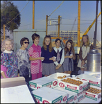 Women Standing in front of Table of Krispy Kreme Doughnuts by Skip Gandy