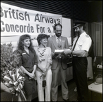 Group Posing in Front of British Airways Sign, F