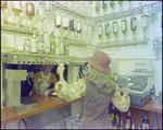 Woman Tending Bar and Operating Cash Register, B by Skip Gandy