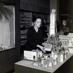 Sales Representative Adjusts Retail Display for Imprevu by Coty Perfume in a Maas Brothers Department Store by George Skip Gandy IV