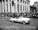 A Buick convertible passes the Exchange National Bank during a parade