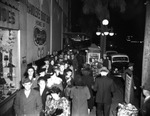 People Stand Outside in Line at Night Beside Handler's Boot Shop by Robertson and Fresh (Firm)