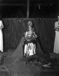 [A pageant queen with roses who is surrounded by palm fronds and her court] by Robertson and Fresh