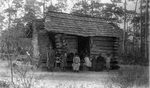 African American family in front of log cabin by C. H. Stokes